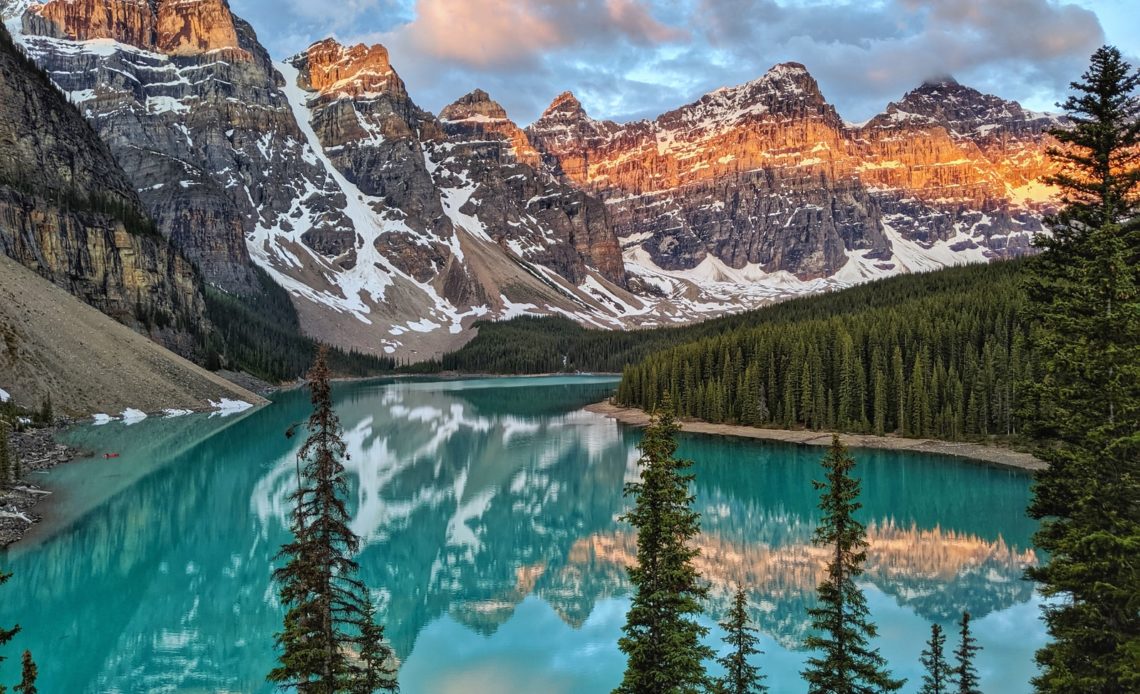 trees near a mountain beside body of water during golden hour