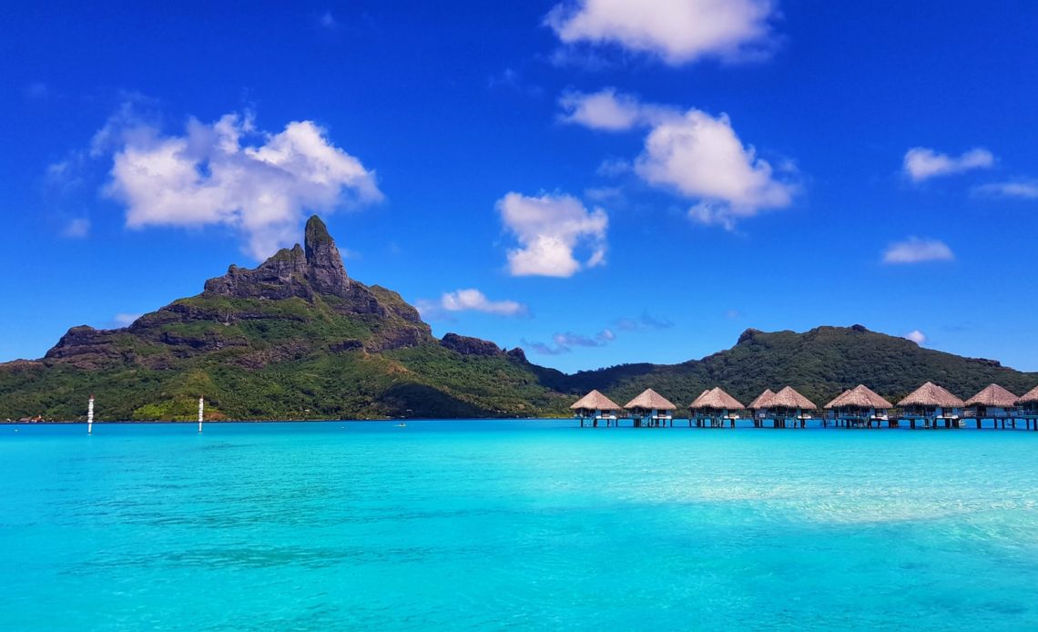 green mountain beside body of water under blue sky during daytime